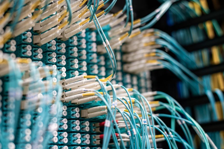 From below of long thin blue cables connected to row of small white connectors on system block in data center